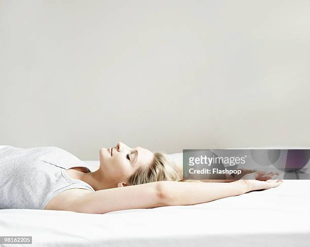 portrait of woman lying on bed - serene people photos stock pictures, royalty-free photos & images
