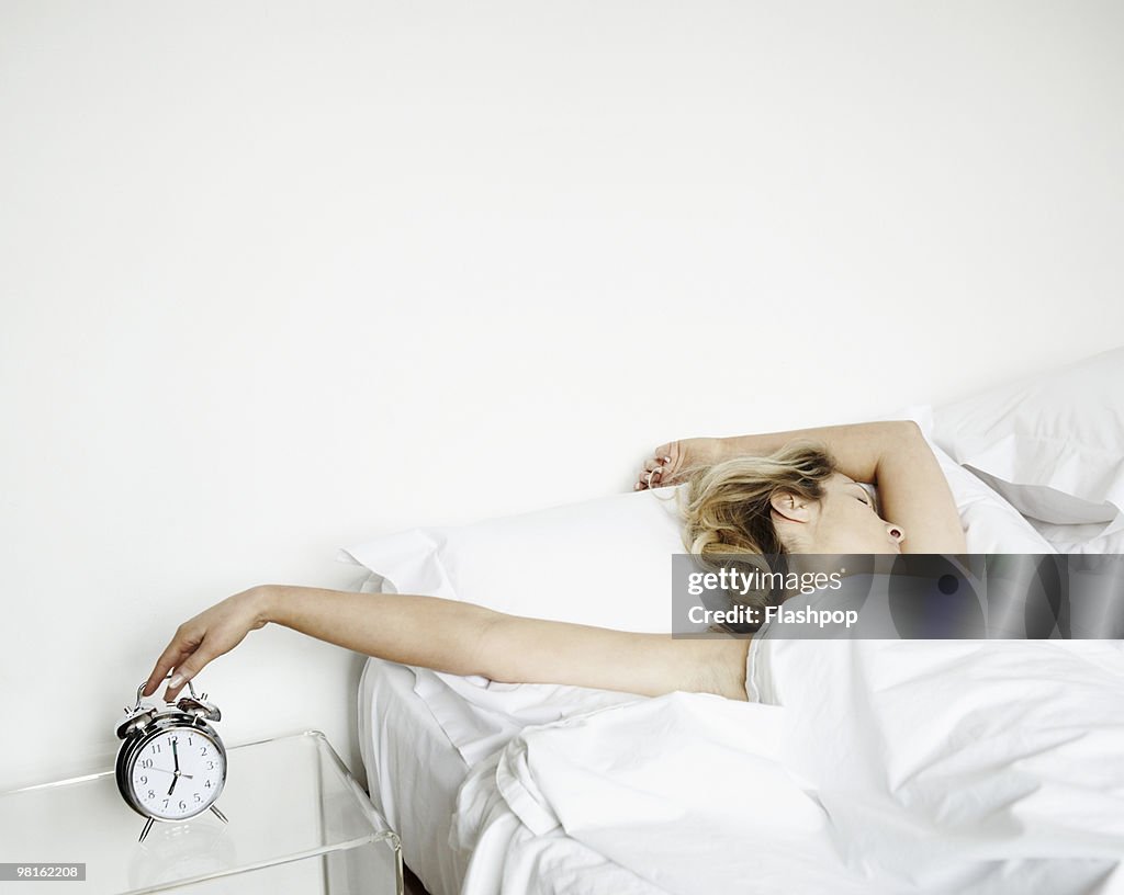 Woman reaching to turn alarm clock off