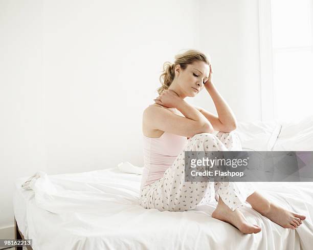portrait of woman feeling tired sitting on bed - fatigue full body stock-fotos und bilder
