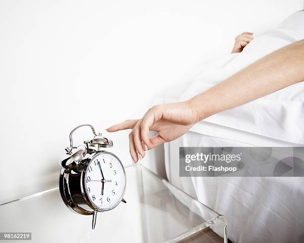 woman reaching to turn off alarm clock - routine stockfoto's en -beelden