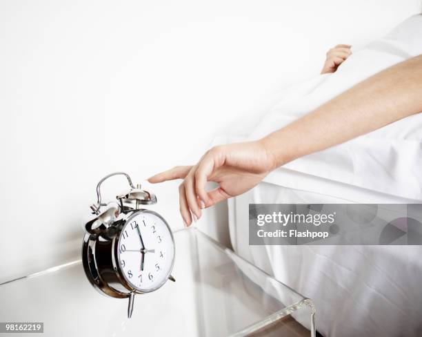 woman reaching to turn off alarm clock - description stock pictures, royalty-free photos & images