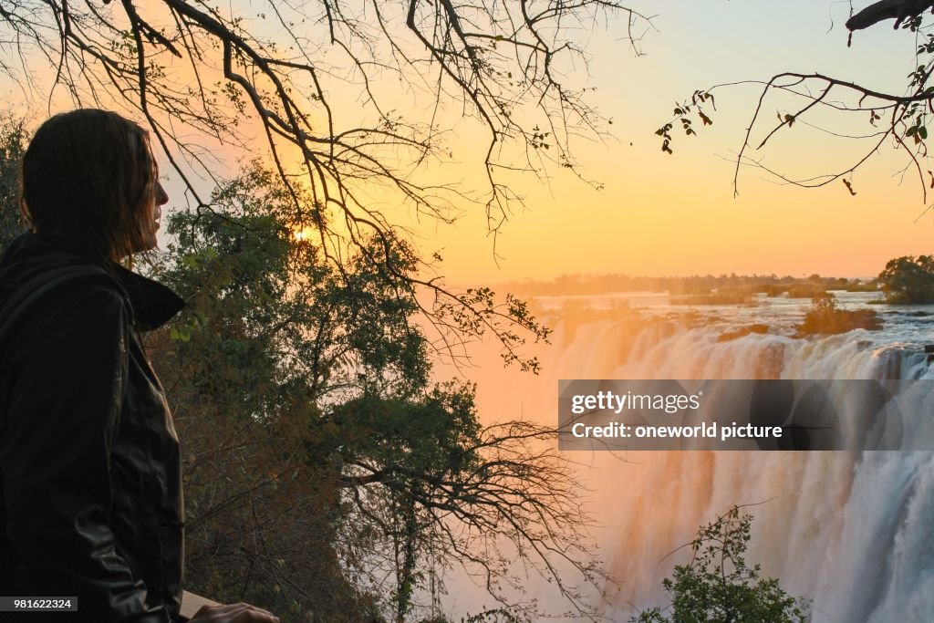 Zambia. Victoria Falls. Sambesi river. girl admires Victoria Falls at sunset