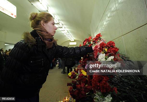 Russian woman lays flowers for the victims of terrorist bomb attacks inside the Lubyanka metro station in Moscow on March 31, 010. Militants will not...