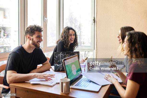 four happy students at desk learning together - estudo imagens e fotografias de stock
