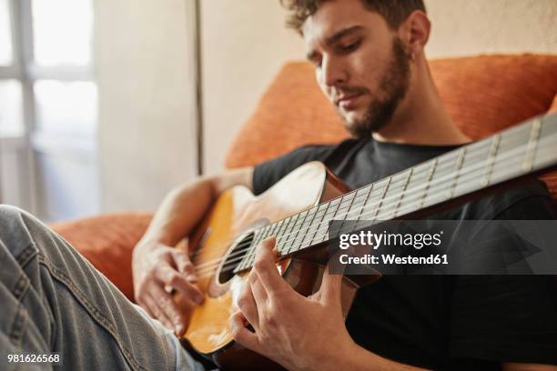 man playing guitar on couch - guitar ストックフォトと画像