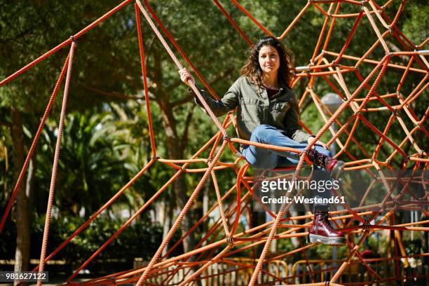 portrait of young woman on a climbing frame on a playground - jungle gym stock pictures, royalty-free photos & images