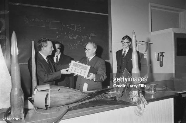 English businessman, chairman and managing director of Racal Electronics Ernest Harrison presents communication receiver to British physic teacher...