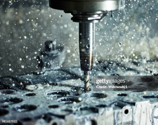 cnc machine drilling into cylinder head with coolant - trapano foto e immagini stock