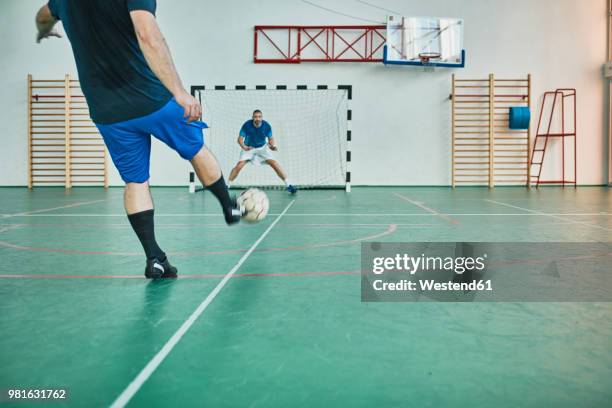 two men playing indoor soccer shooting at goal - hallenfußball wettbewerb stock-fotos und bilder