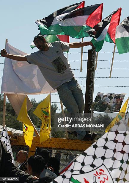 Palestinian protester shouts slogans as he stands on a fence bearing Palestinian flags during clashes with Israeli soldiers at the Betunia checkpoint...