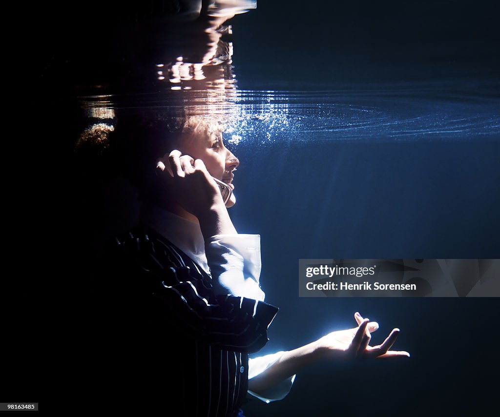 Businesswoman talking on cellphone underwater