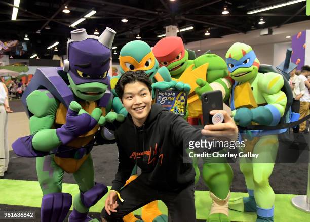 Olympian Ice Dancer Alex Shibutani poses with Nickelodeon's "Rise of the Teenage Mutant Turtles" costumed characters at Nickelodeon's booth at 2018...
