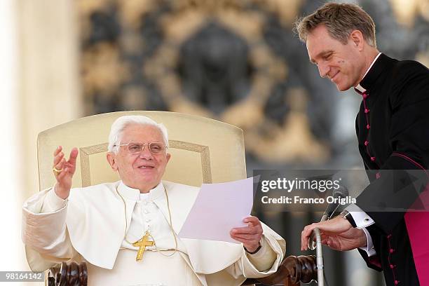 Pope Benedict XVI, flanked by his personal secretary Monsignor Georg Gaenswein, waves to the faithful gathered in St. Peter's square during his...
