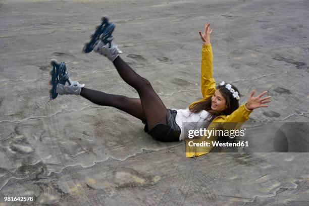 smiling woman with inline skates falling on ground - inline skating - fotografias e filmes do acervo