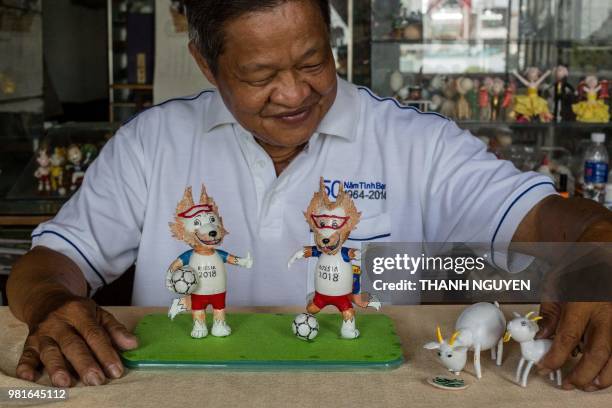 This picture taken on June 20, 2018 shows retired Vietnamese English teacher Nguyen Thanh Tam displaying two finished models of Zabivaka , the 2018...