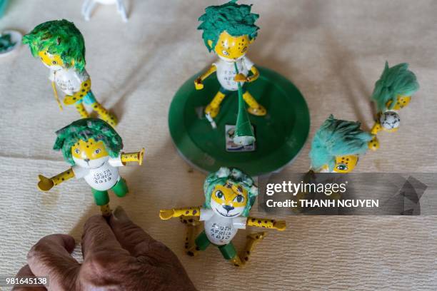 This picture taken on June 20, 2018 shows retired Vietnamese English teacher Nguyen Thanh Tam displaying models of Zakumi, the 2010 South African...