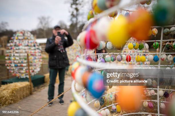 March 2018, Germany, Ludwigsburg: A man takes a picture of the Easter egg avenue at the exhibition 'Strohwelten' at the 'Bluehendes Barock' . More...