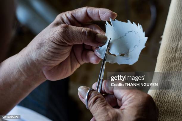 This picture taken on June 20, 2018 shows retired Vietnamese English teacher Nguyen Thanh Tam making paper cutouts as he creates a model of Zabivaka,...