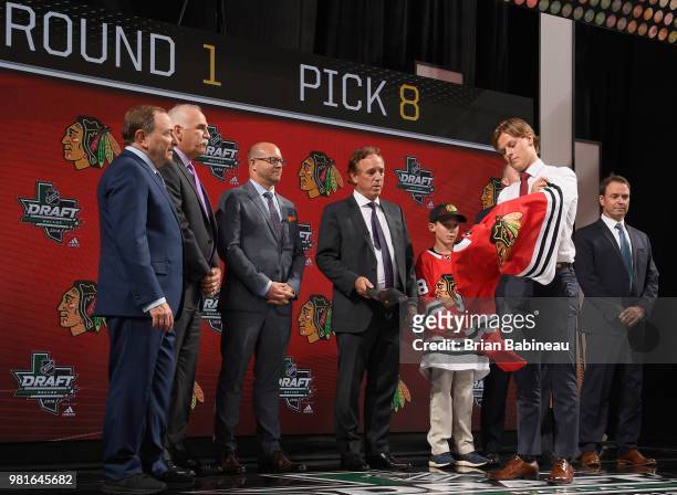 Adam Boqvist puts on a Chicago Blackhawks jersey onstage after being selected eighth overall by the Chicago Blackhawks during the first round of the...