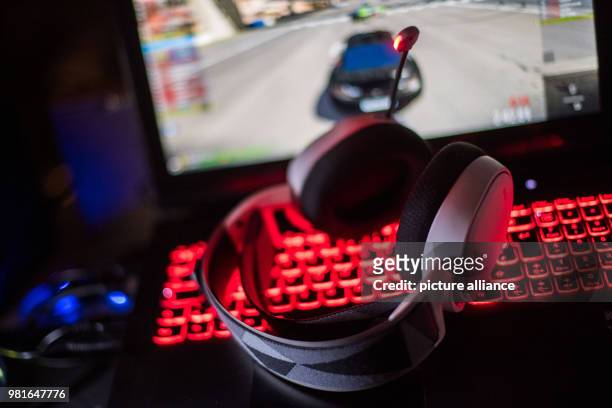 March 2018, Germany, Munich: Gaming headphones lie on a gaming laptop. On the screen a racing game can be seen. Photo: Lino Mirgeler/dpa