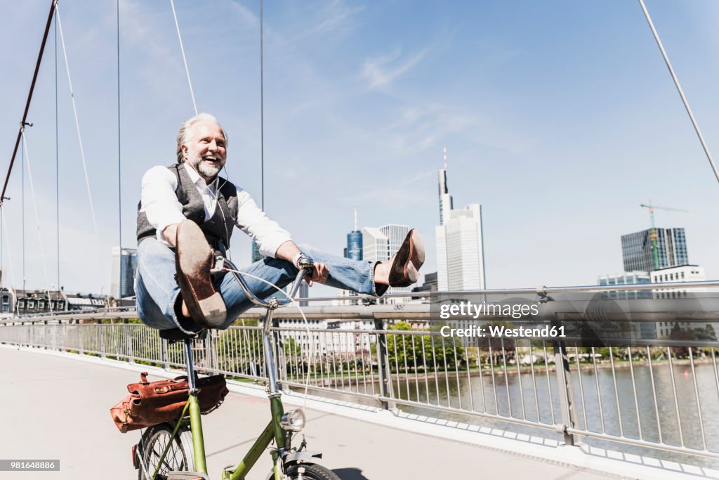 Playful mature man on bicycle on bridge in the city
