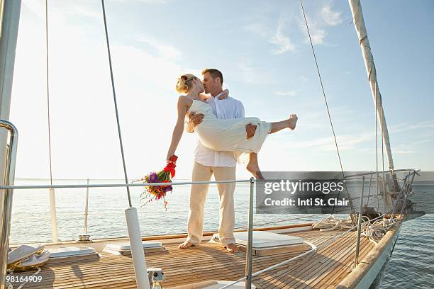 groom lifting bride up, kissing, on sailboat - inti st clair stock pictures, royalty-free photos & images