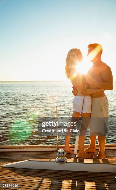 couple embracing on sailboat at sunset - inti st clair stock pictures, royalty-free photos & images