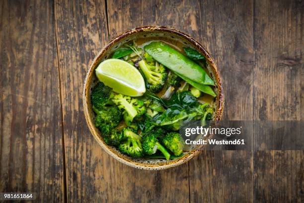 bowl of green thai curry with broccoli, pak choi, snow peas, baby spinach and lime - fresh baby spinach stock-fotos und bilder