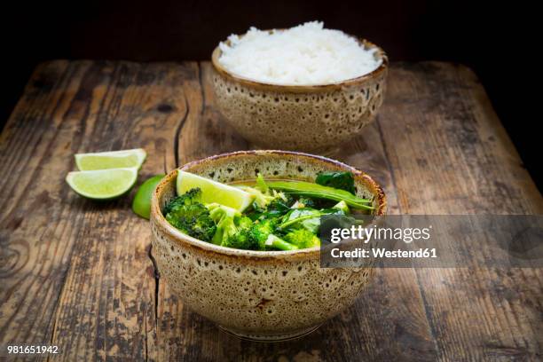 green thai curry with broccoli, pak choi, snow peas, baby spinach, lime and bowl of rice in the background - fresh baby spinach stock pictures, royalty-free photos & images