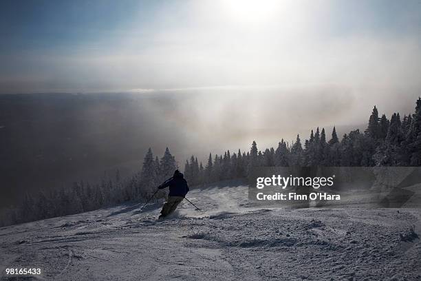 skiier heading down the mountain, into the sun. - mont tremblant ski village stock pictures, royalty-free photos & images