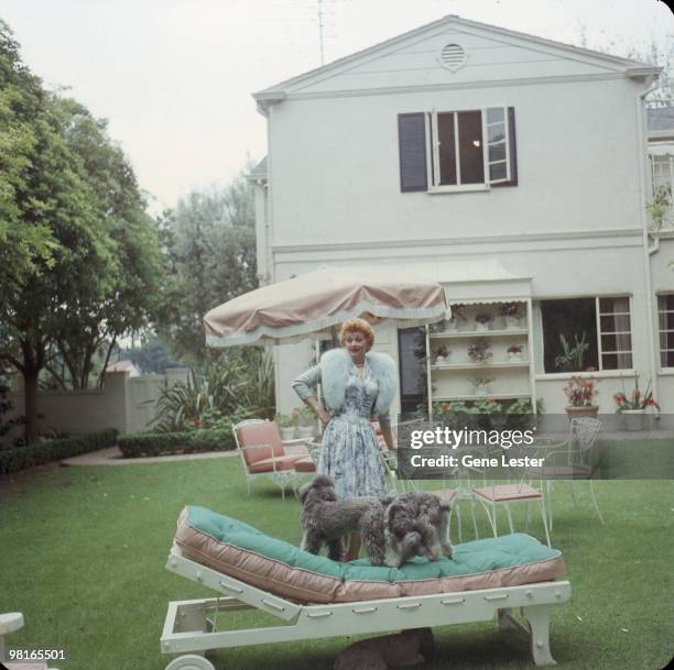 American actress and comedienne Lucille Ball plays with her dogs in the back garden of her home, Los Angeles, California, late 1950s.