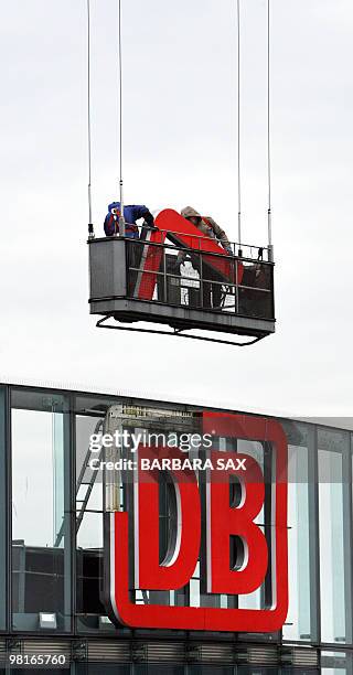 Picture taken on November 22, 2007 in Berlin shows workers removing parts of the logo of Germany's state-owned rail operator Deutsche Bahn at the...