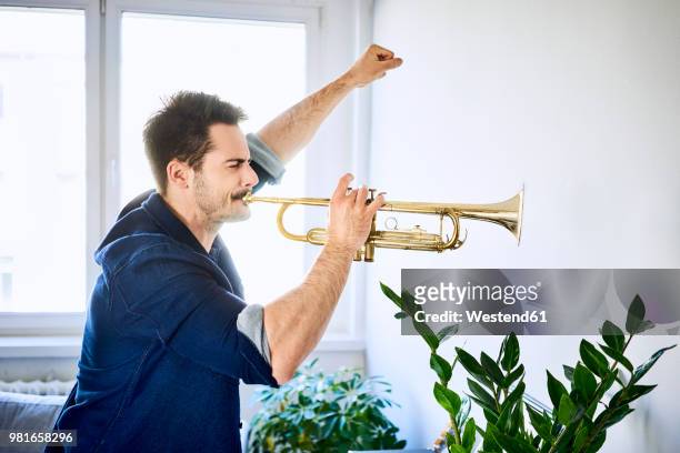 man at home playing trumpet - bad neighbor foto e immagini stock