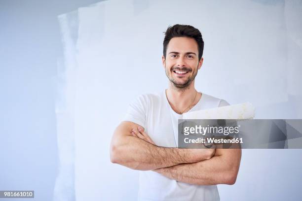portrait of smiling man painting wall in apartment - peintre photos et images de collection