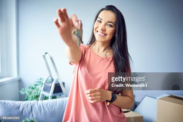 portrait of happy woman moving in showing keys to new apartment - house key hands stock pictures, royalty-free photos & images