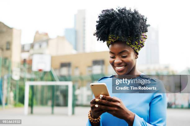 woman using smart phone in city - black woman laughing stock pictures, royalty-free photos & images