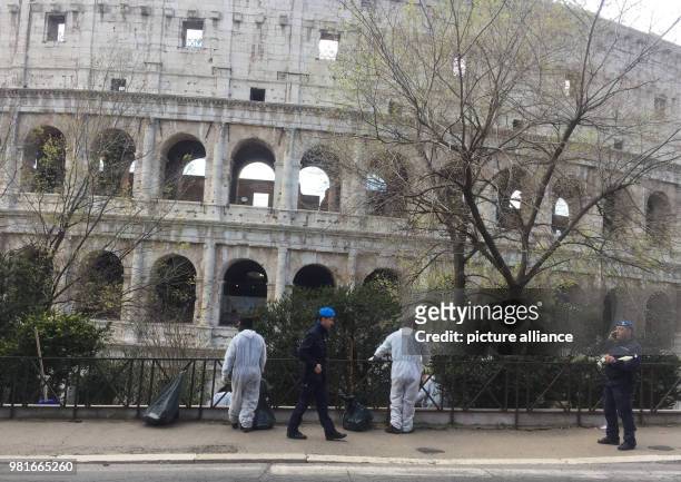 March 2018, Italy, Rome: Prisoners removing rubbish from an area next to the collosseum whilst being monitored by police officers. Romes decline is...