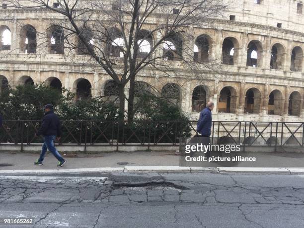 March 2018, Italy, Rome: Pedestrians walking by a pothole in front of the colloseum. Romes decline is legendary. But now prisoners have been put to...