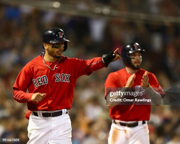 Mookie Betts of the Boston Red Sox points and Blake Swihart of the Boston Red Sox applauds at J.D. Martinez of the Boston Red Sox on first base after...