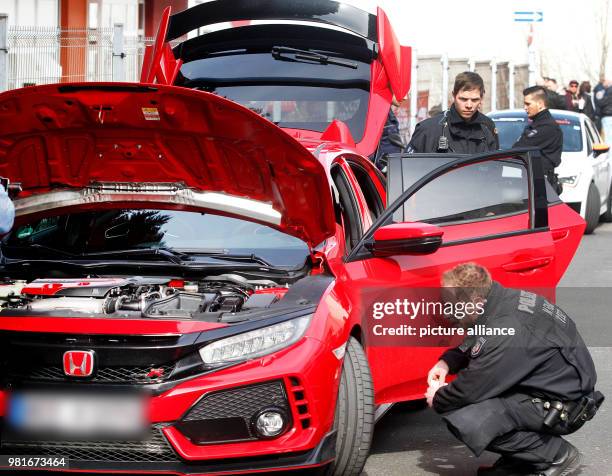 March 2018, Germany, Bochum: A police office checks a car at a large meet-up of car tuners. Photo: Roland Weihrauch/dpa - ATTENTION EDITORS: Licence...