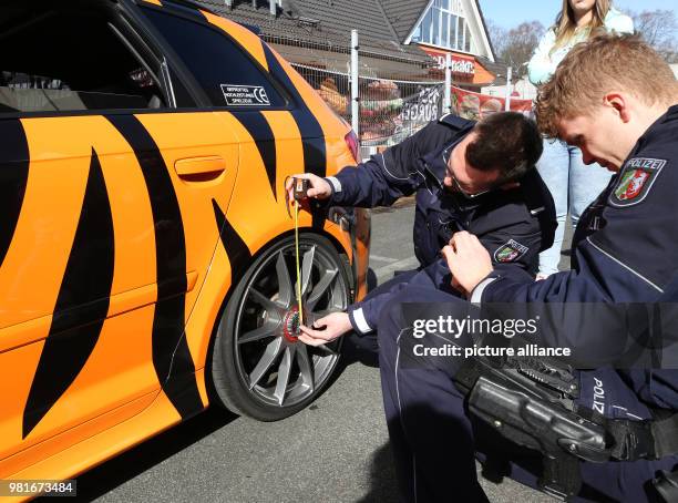 March 2018, Germany, Bochum: A police officers check a car at a large meet-up of car tuners. Photo: Roland Weihrauch/dpa - ATTENTION EDITORS: License...