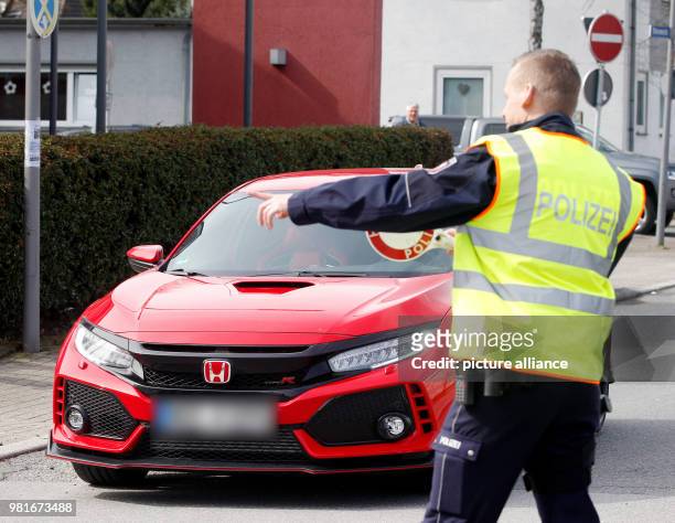 March 2018, Germany, Bochum: A police office checks a car at a large meet-up of car tuners. Photo: Roland Weihrauch/dpa - ATTENTION EDITORS: Licence...