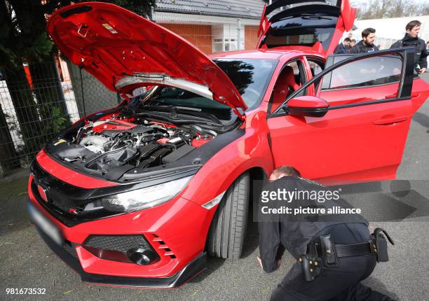 March 2018, Germany, Bochum: A police officers check a car at a large meet-up of car tuners. Photo: Roland Weihrauch/dpa - ATTENTION EDITORS: License...