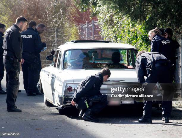 March 2018, Germany, Bochum: A police officers check a car at a large meet-up of car tuners. Photo: Roland Weihrauch/dpa - ATTENTION EDITORS: License...