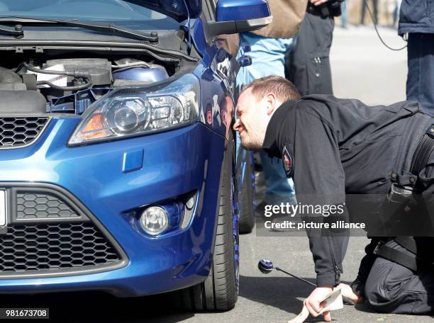 March 2018, Germany, Bochum: A police officer checks a car at a large meet-up of car tuners. Photo: Roland Weihrauch/dpa - ATTENTION EDITORS: License...