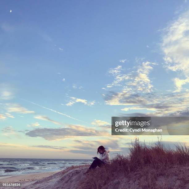 girl reading on beach at sunset - roman landscapes stockfoto's en -beelden