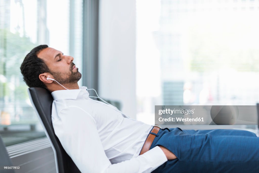 Businessman with earphones, closed eyes