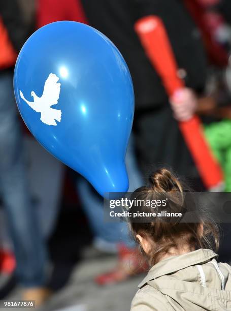 March 2018, Germany, Duisburg: A girl holding a balloon with the peace dove during the Rhine-Ruhr Easter March for disarmament. Photo: Caroline...