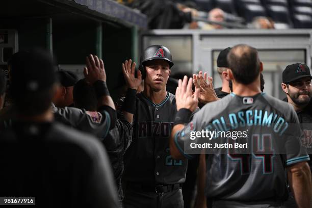 Jake Lamb of the Arizona Diamondbacks is greeted by teammates in the dugout after coming around to score in the eleventh inning during the game...