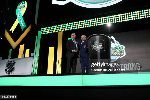 Kevin Garinger, president of the Humboldt Broncos, and NHL commissioner Gary Bettman shake hands onstage after accepting the EJ McGuire Award of...